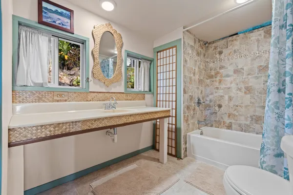 a bathroom with a granite countertop sink a mirror a bathtub and a shower