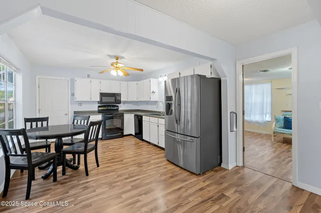 a kitchen with stainless steel appliances a dining table chairs refrigerator and a window