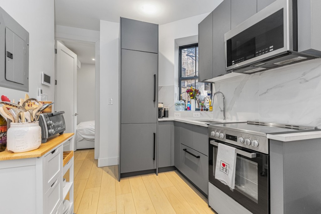 356 West 48th Street, Unit 2C Manhattan, NY 10036 - Photo 5 of 25 a kitchen with stainless steel appliances granite countertop a stove and a microwave