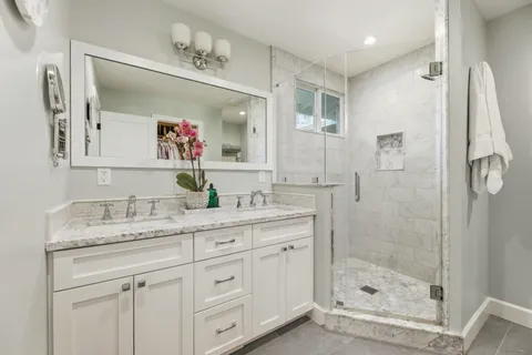 a bathroom with a granite countertop sink mirror and shower