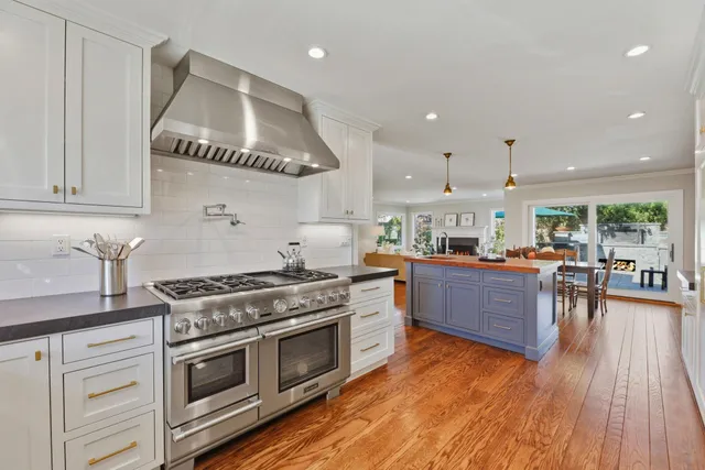 a kitchen with stainless steel appliances granite countertop a stove and a wooden floors