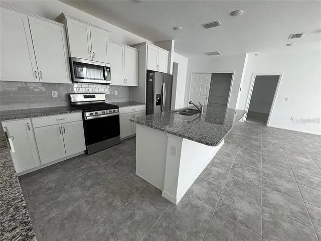 a large white kitchen with kitchen island a stove a sink dishwasher and a refrigerator