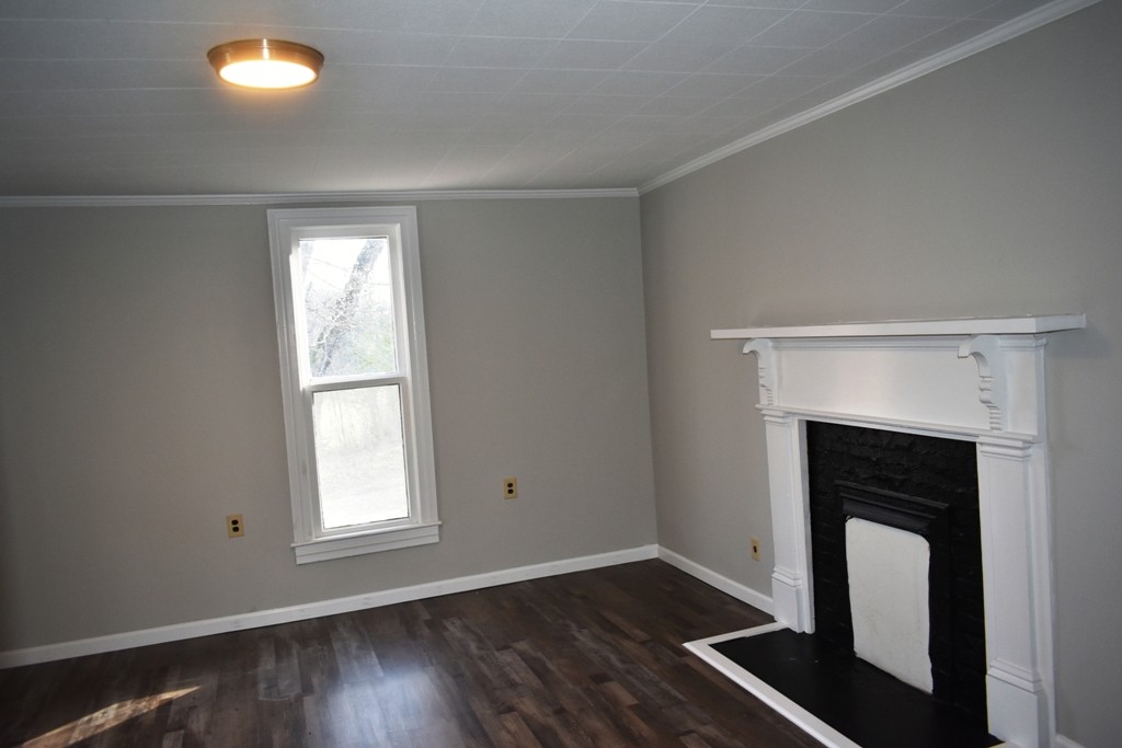 5 Dog Branch Road Pleasant Shade, TN 37145 - Photo 3 of 8 an empty room with wooden floor fireplace and windows