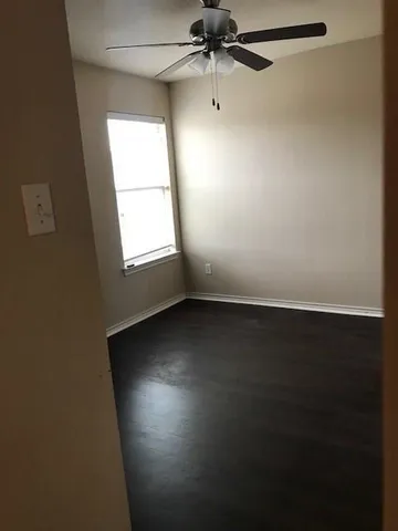 an empty room with a window and a fan