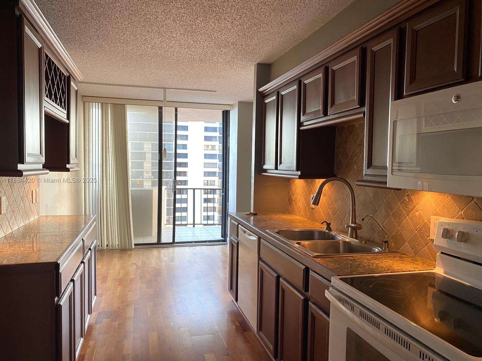 4200 North Ocean Drive, Unit 11103 Riviera Beach, FL 33404 - Photo 6 of 11 a kitchen that has a sink wooden cabinets and stainless steel appliances