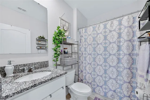 a bathroom with a granite countertop sink and a toilet