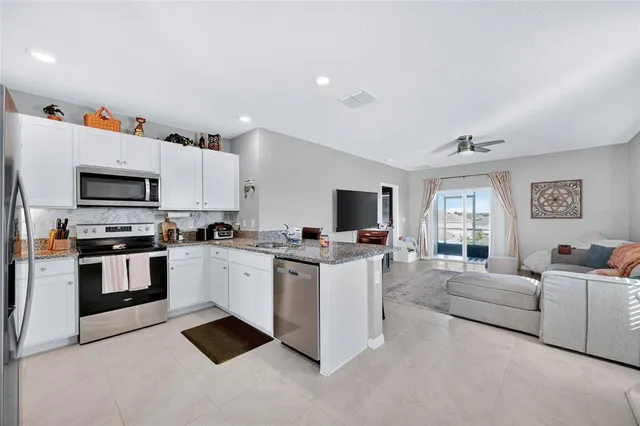 a view of living room with furniture a flat screen tv and kitchen view