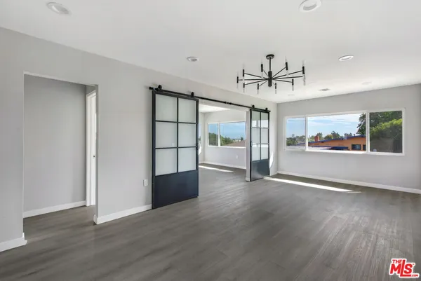 a view of an empty room with wooden floor and windows