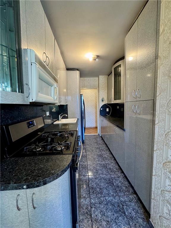 458 Neptune Avenue, Unit 3K Brooklyn, NY 11224 - Photo 10 of 12 a kitchen with stainless steel appliances granite countertop a stove a sink and a microwave