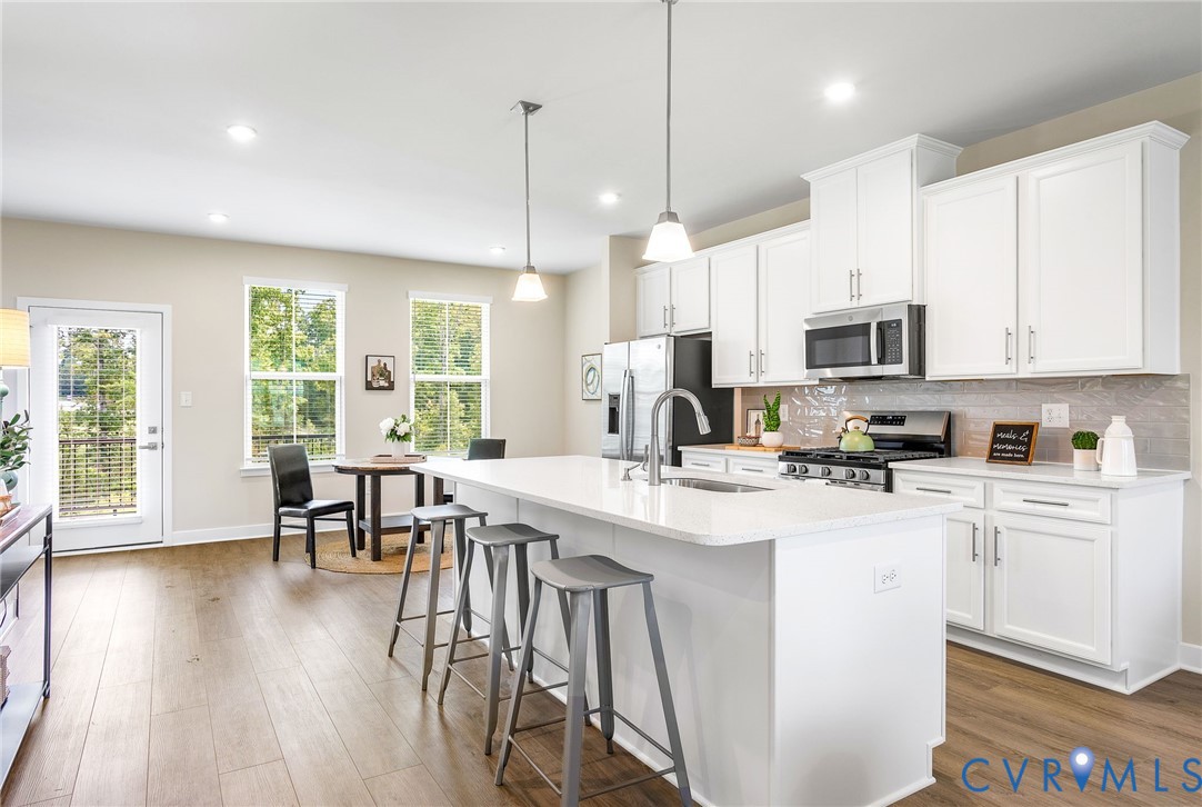 1255 Lazy River Road Midlothian, VA 23114 - Photo 10 of 27 a kitchen with stainless steel appliances granite countertop a stove top oven a sink a dining table and chairs with wooden floor