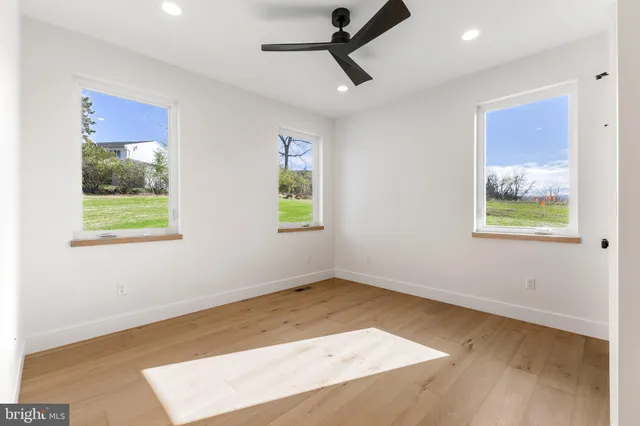 a view of empty room with wooden floor and ceiling fan