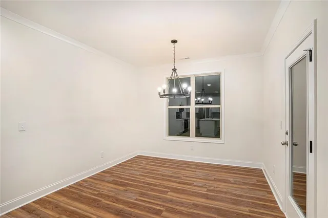 a view of empty room with wooden floor and kitchen