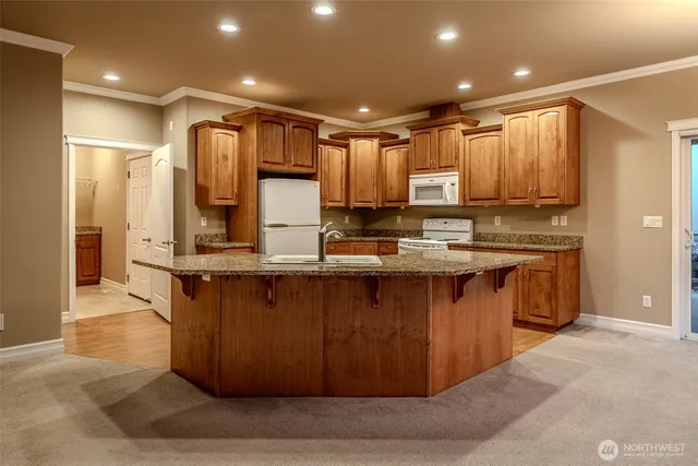 a kitchen with stainless steel appliances kitchen island granite countertop a stove a sink and a refrigerator