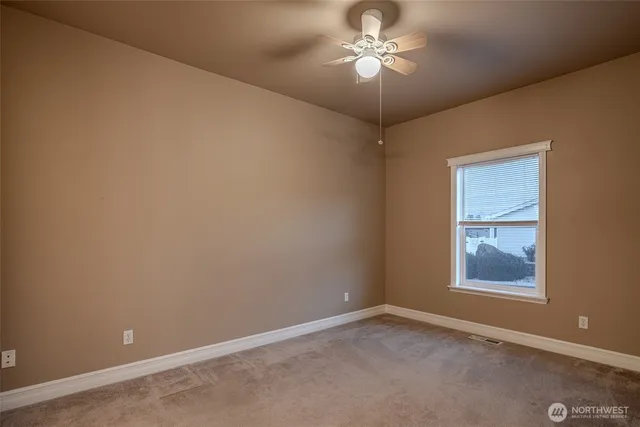an empty room with a window and a fan