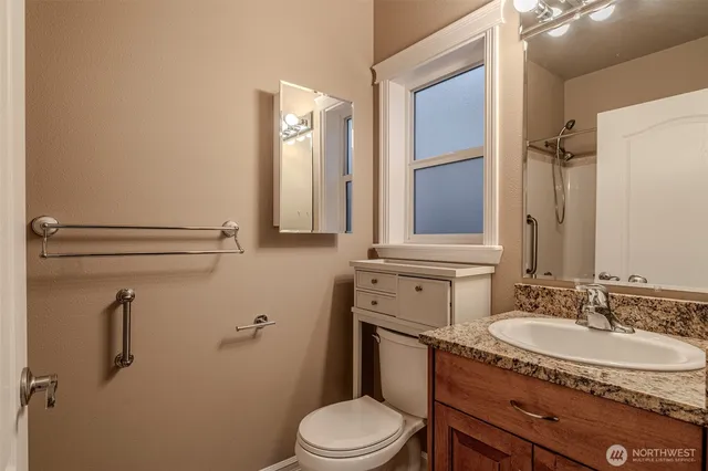a bathroom with a granite countertop sink toilet and mirror
