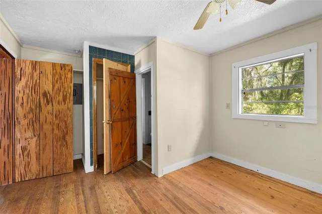 a view of empty room with wooden floor and fan