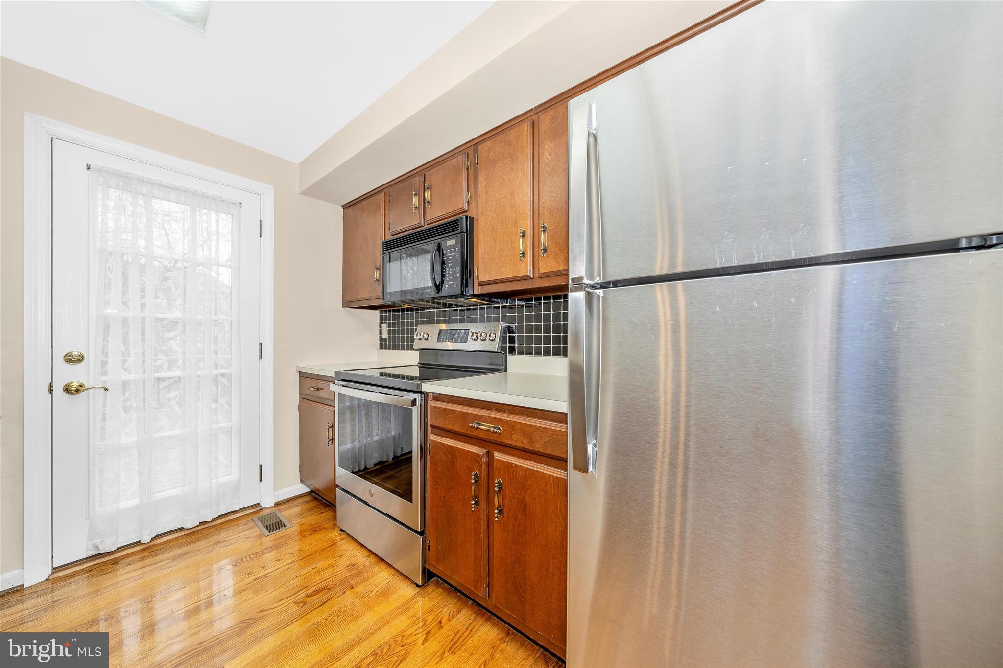 8007 Broken Reed Court Frederick, MD 21701 - Photo 18 of 72 a kitchen with stainless steel appliances granite countertop a refrigerator a stove and a sink with wooden floor