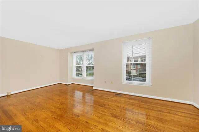 a view of an empty room with wooden floor and stairs
