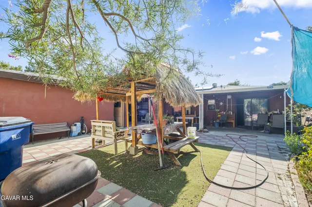a view of a patio with table and chairs potted plants and large tree