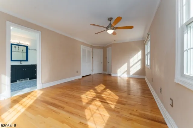 a view of empty room with wooden floor and fan