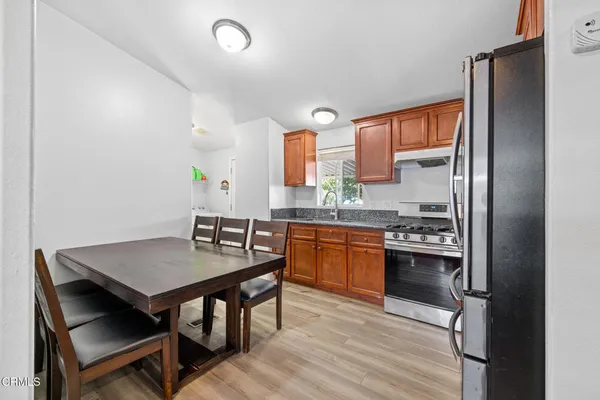 a kitchen with granite countertop a stove a sink dishwasher and a refrigerator with wooden floor