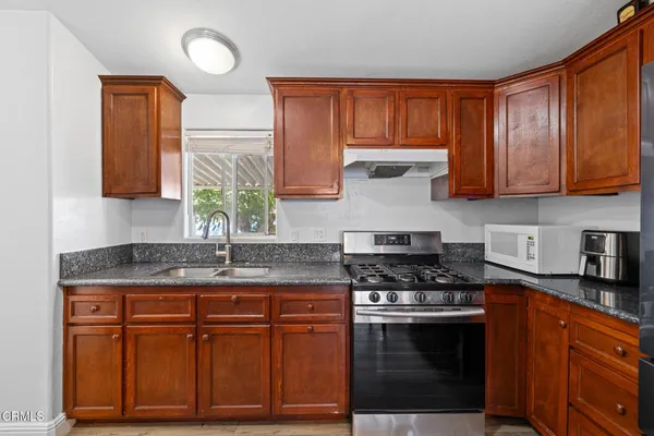 a kitchen with stainless steel appliances granite countertop a stove a sink and a microwave