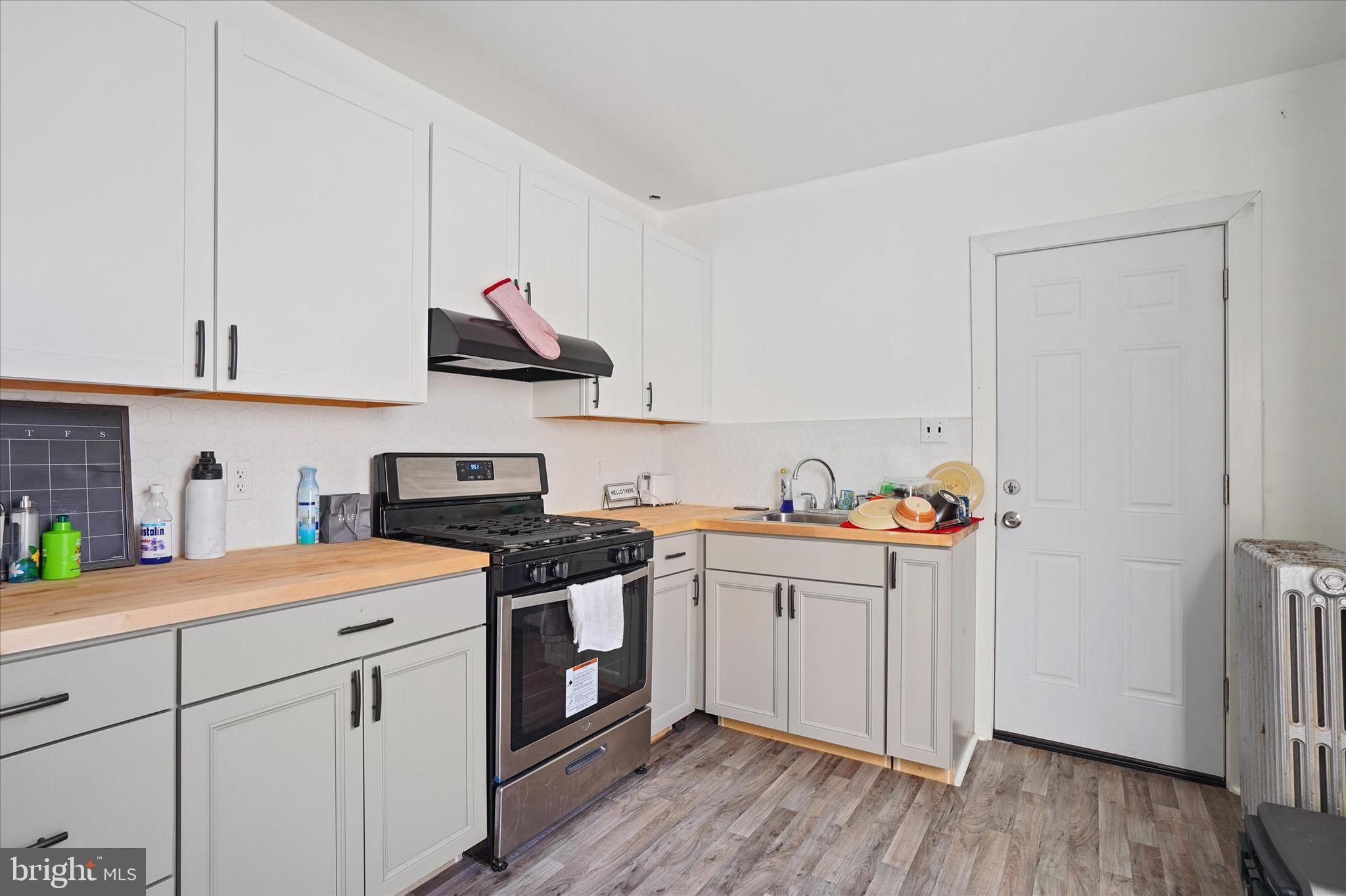 933 North 12th Street Reading, PA 19604 - Photo 21 of 26 a kitchen with a white cabinets a sink and wooden floor