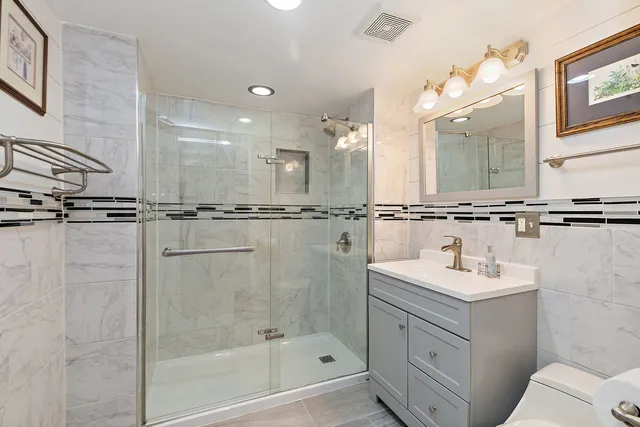 a bathroom with a sink a toilet a mirror and shower