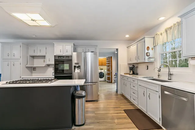 a large kitchen with stainless steel appliances kitchen island granite countertop a sink and cabinets