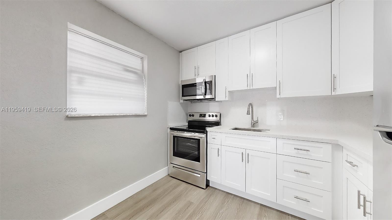329 Southwest 9th Avenue Miami, FL 33130 - Photo 91 of 97 a kitchen with white cabinets stainless steel appliances and wooden floor