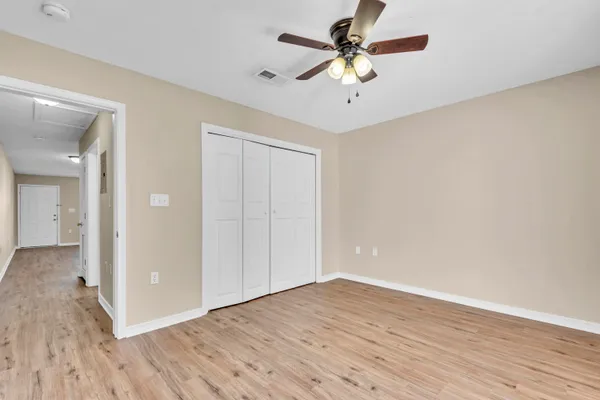 a view of a big room with wooden floor and a chandelier fan