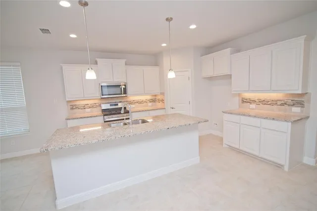 a kitchen with stainless steel appliances granite countertop a sink a stove and a wooden floors
