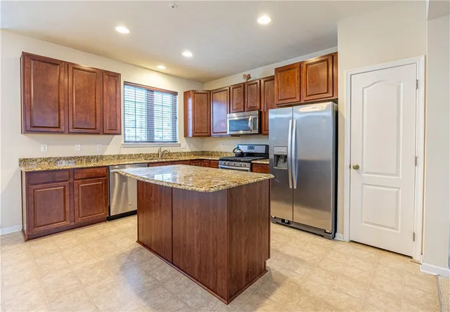 a kitchen with stainless steel appliances granite countertop a refrigerator and a stove