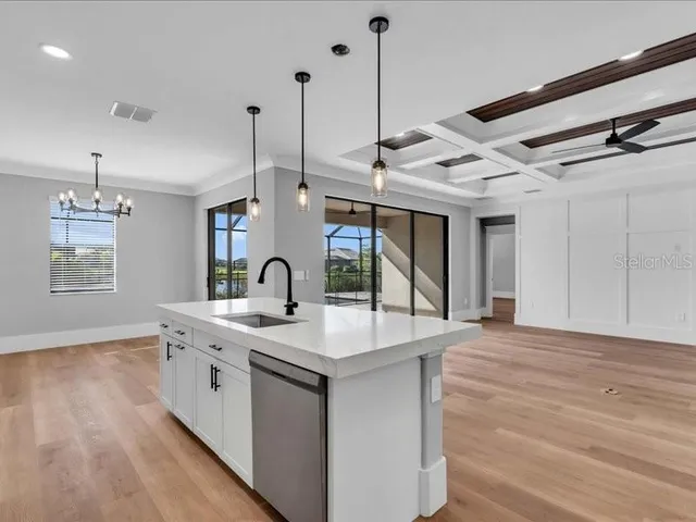 a kitchen with stainless steel appliances granite countertop a sink a stove and a wooden floor