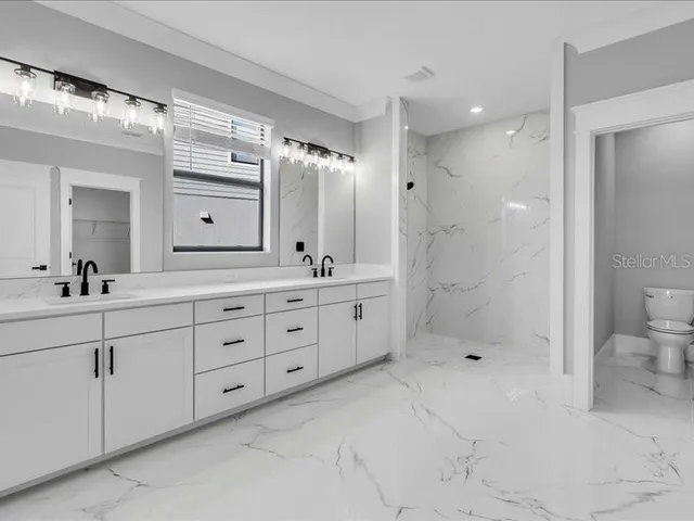 a spacious bathroom with double sink shower and a mirror