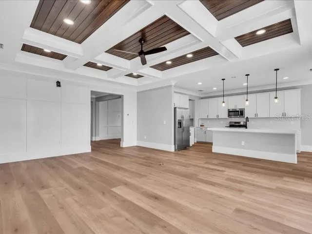 a view of an empty room with kitchen and a window