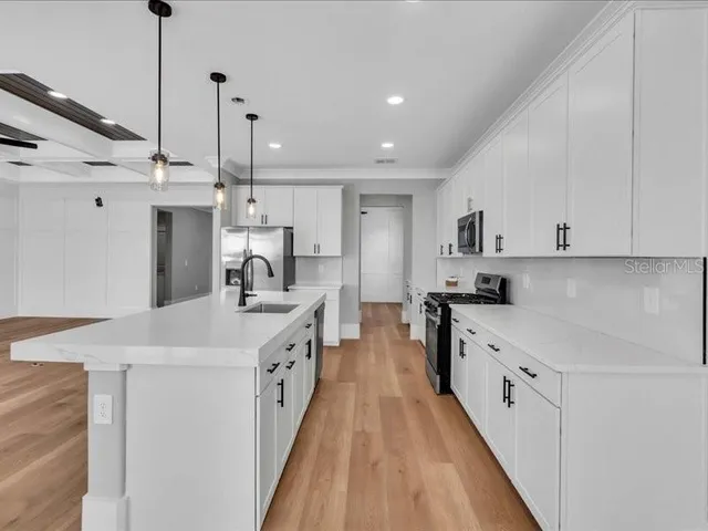 a kitchen with white cabinets sink and stainless steel appliances