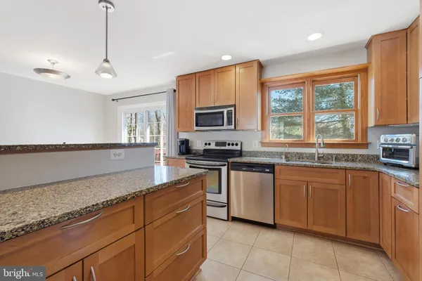 a kitchen with stainless steel appliances granite countertop a stove a sink and a microwave