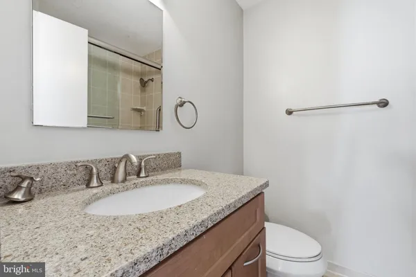 a bathroom with a granite countertop sink a toilet and a mirror