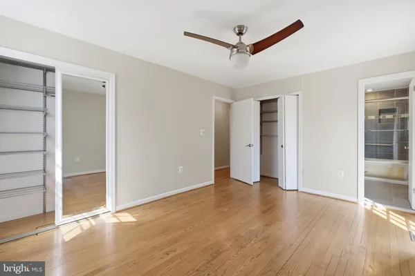 an empty room with wooden floor and a ceiling fan