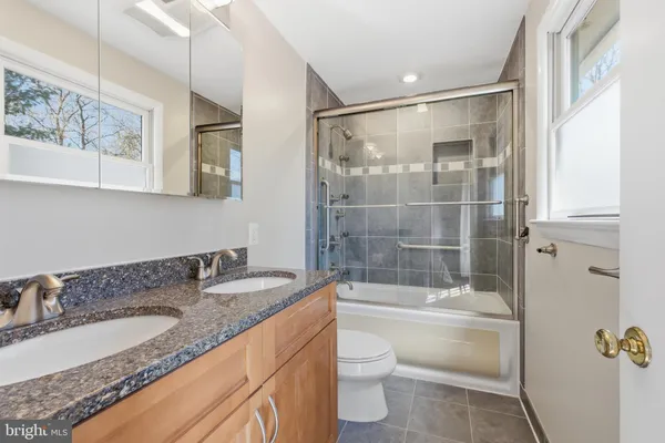 a bathroom with a granite countertop sink toilet and shower