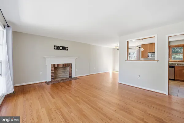 a view of empty room with wooden floor and fireplace