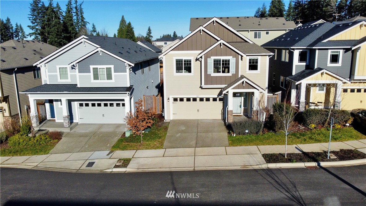 4411 236th Place Southeast Bothell, WA 98021 - Photo 29 of 31 a view of a white house with a large windows and a yard with plants and large trees