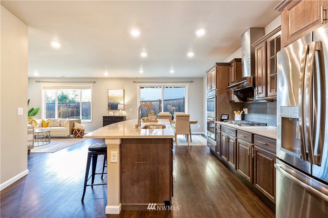 4411 236th Place Southeast Bothell, WA 98021 - Photo 7 of 31 a kitchen with stainless steel appliances granite countertop a stove top oven a refrigerator a sink a dining table and chairs with wooden floor