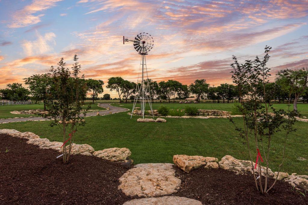 11167 Plainview Road Krum, TX 76249 - Photo 7 of 40 Expansive green space featuring a decorative windmill, meandering paved pathways, and mature trees lining the perimeter