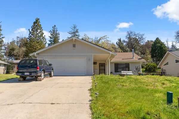 a view of a house with a yard and large trees