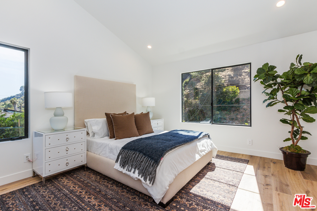 2084 Roscomare Road Los Angeles, CA 90077 - Photo 15 of 22 a bedroom with a large bed and a potted plant