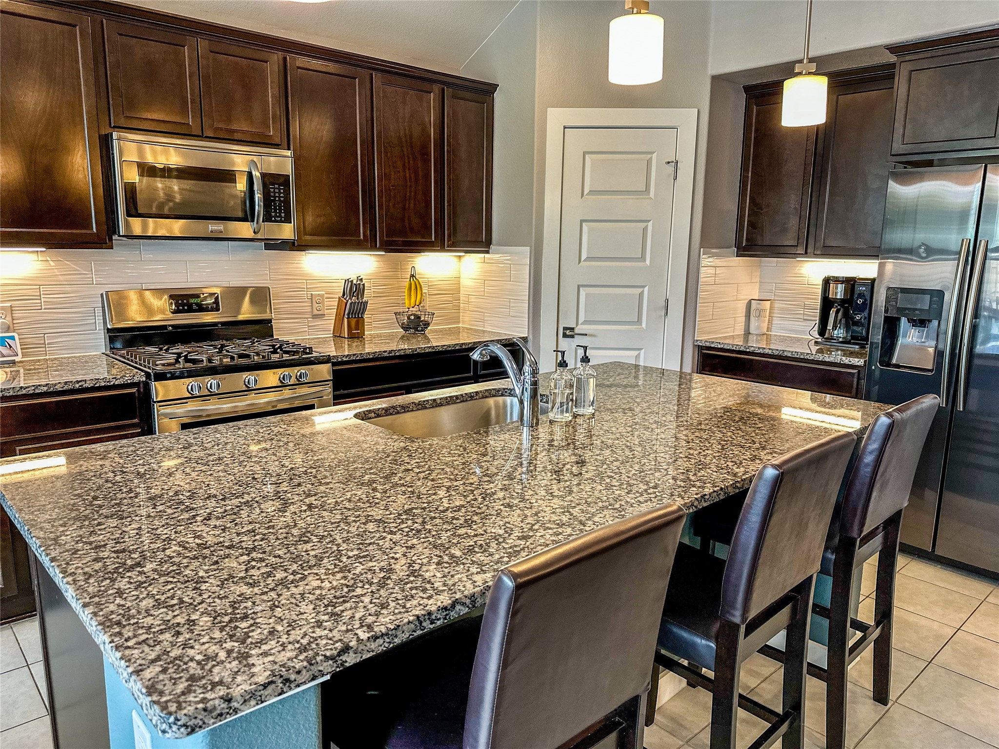 7216 Sienna Rouge Path Austin, TX 78744 - Photo 2 of 37 a kitchen with stainless steel appliances kitchen island granite countertop a stove top oven a sink a counter space and cabinets