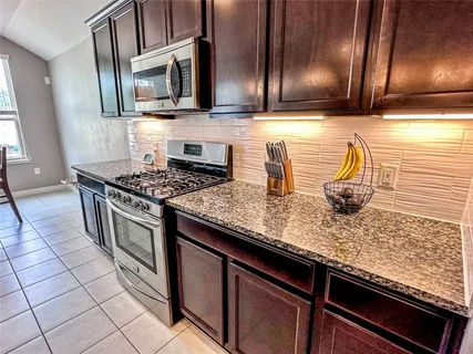 a kitchen with stainless steel appliances granite countertop a sink stove and microwave