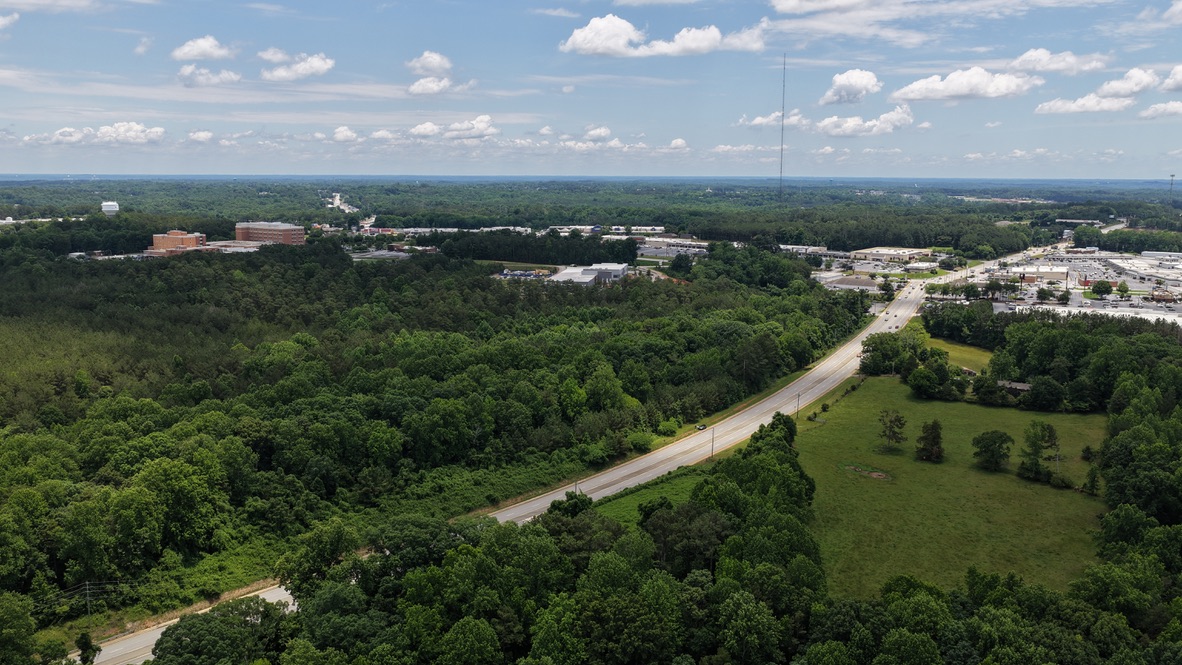 1 Sheep Farm Road Seneca, SC 29678 - Photo 4 of 5 An aerial panorama reveals a verdant landscape with extensive wooded areas and a distant commercial development.